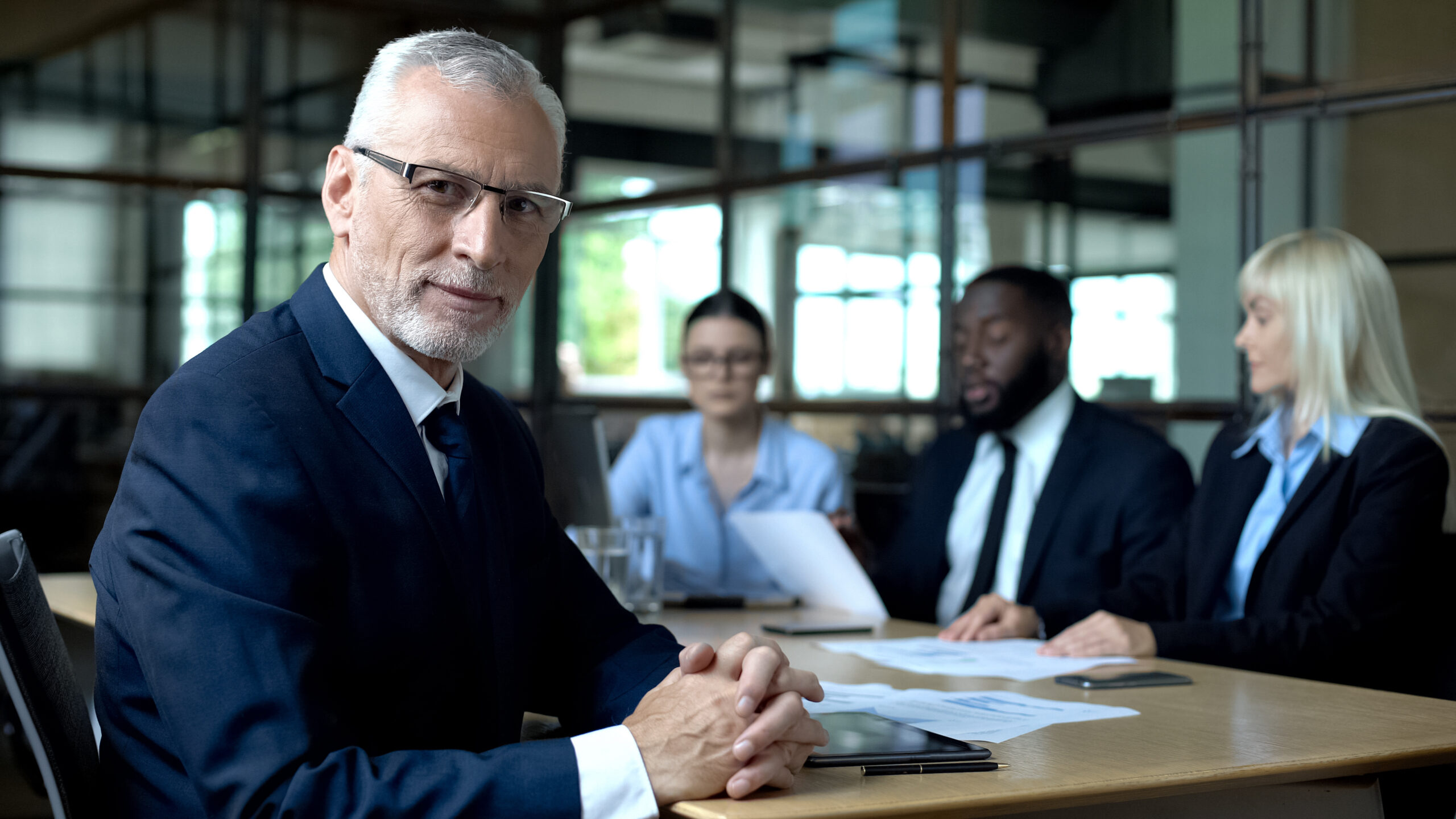 Directeur aan vergadertafel met drie andere leden van het team.
